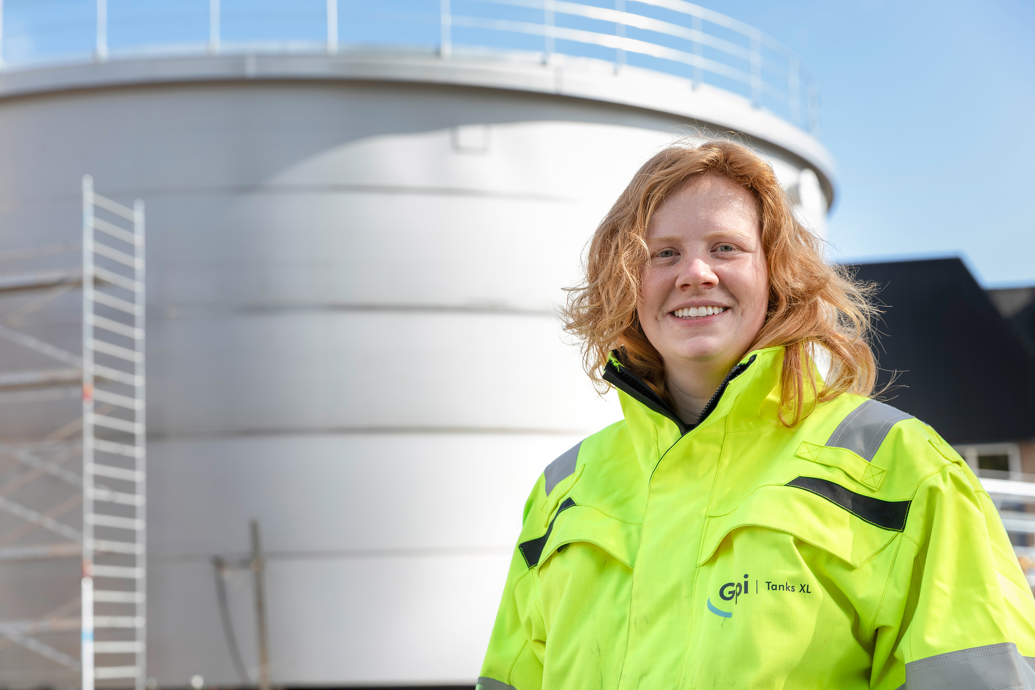 Supervisor Britt bij een grote rvs opslagtank op een tankbouwsite.